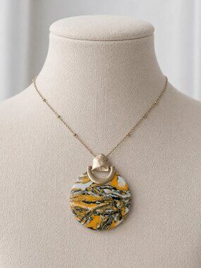 A stylish necklace featuring a large, Art Nouveau-style marbled pendant